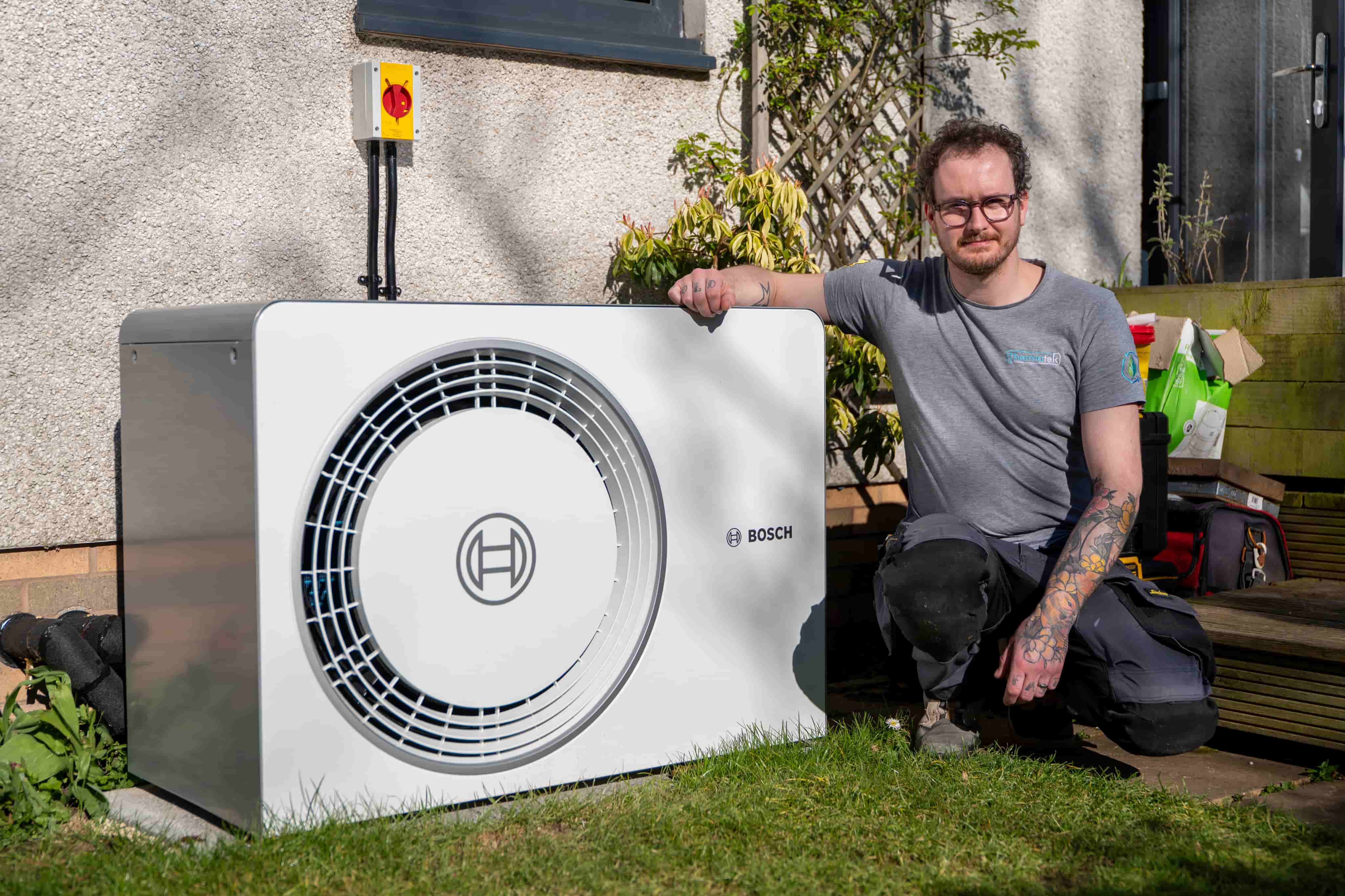 A heating engineer standing beside a newly installed heat pump